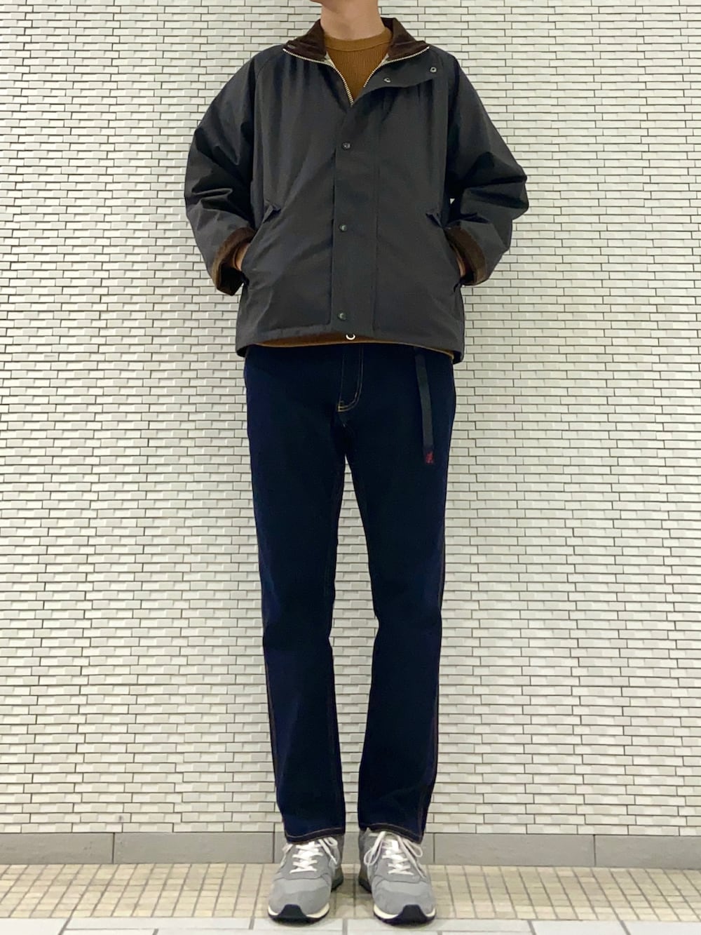 グリーン系のダウンジャケット/コート、オレンジ系のTシャツ/カットソー、ブルー系のその他パンツを着用したメンズの秋コーディネートの2枚目の写真