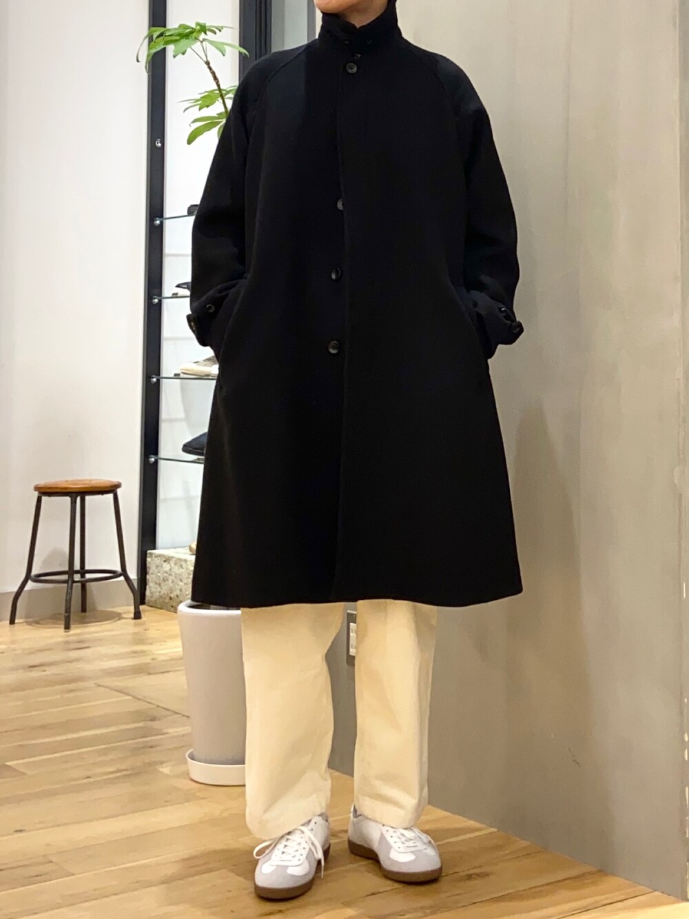 ブラック系のステンカラーコート、レッド系のニット/セーター、ホワイト系のその他パンツを着用したメンズの秋コーディネートの3枚目の写真