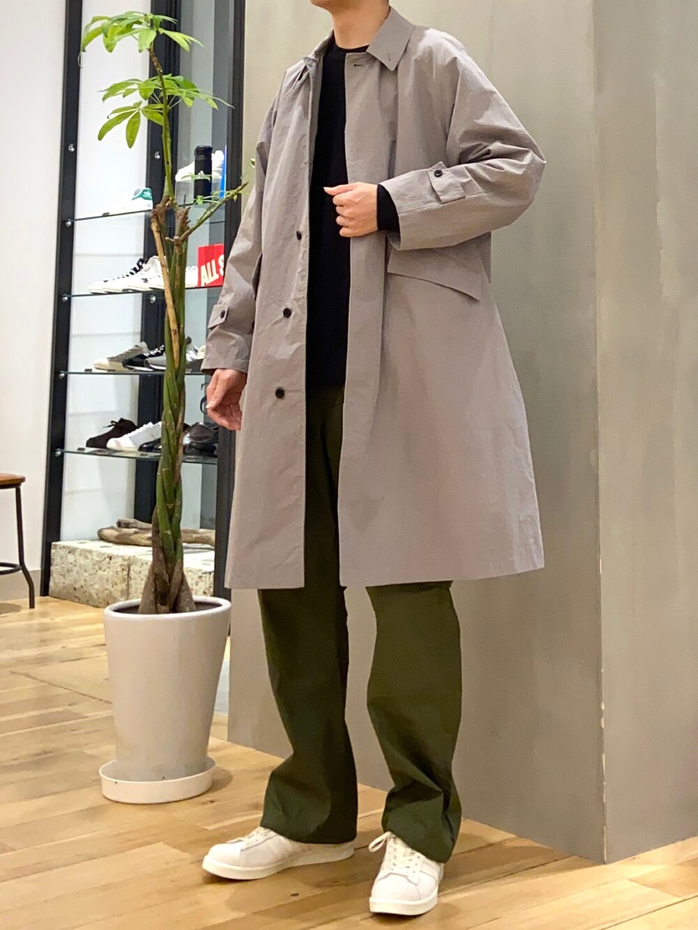 グレー系のステンカラーコート、グリーン系のその他パンツ、ベージュ系のスニーカーを着用したメンズの春コーディネートの4枚目の写真