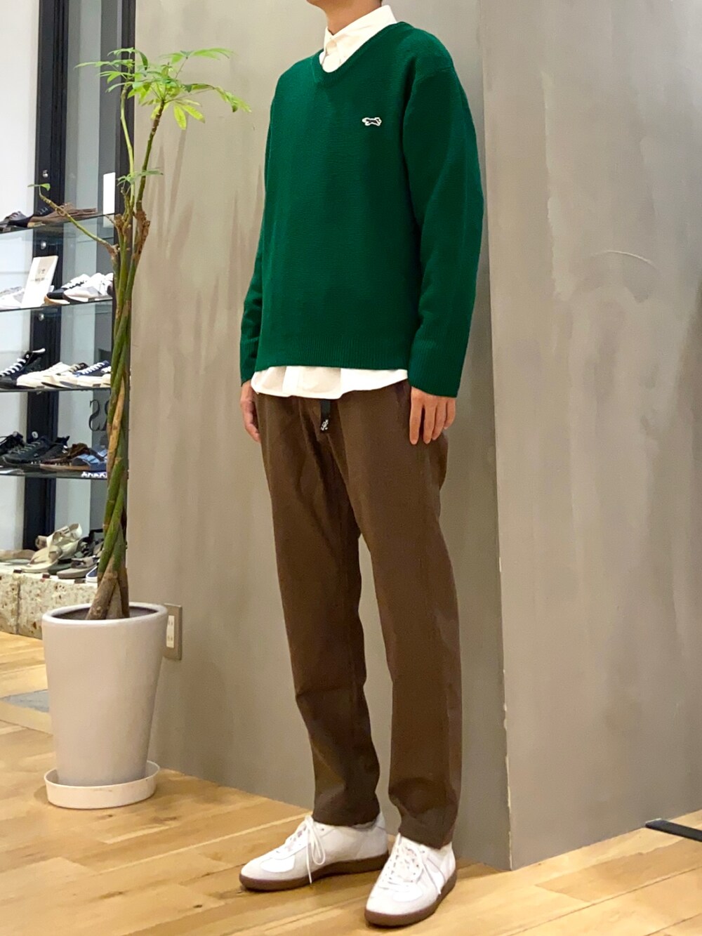 グリーン系のニット/セーター、ホワイト系のシャツ/ブラウス、ホワイト系のスニーカーを着用したメンズの秋コーディネートの3枚目の写真