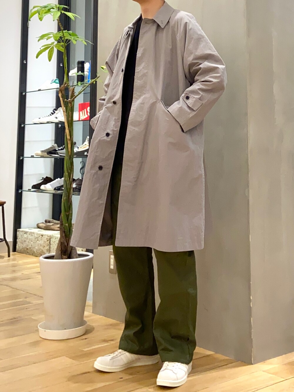 グレー系のステンカラーコート、グリーン系のその他パンツ、ベージュ系のスニーカーを着用したメンズの春コーディネートの2枚目の写真