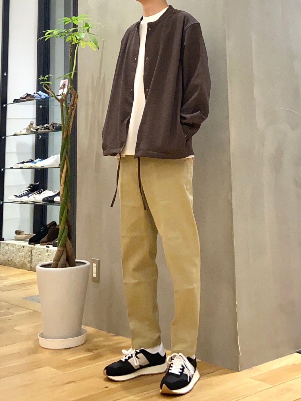 ブラウン系のブルゾン、ホワイト系のTシャツ/カットソー、ブラック系のスニーカーを着用したメンズの秋コーディネートの2枚目の写真
