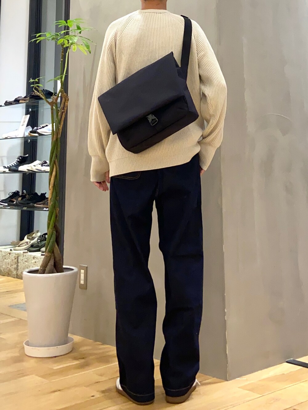 ホワイト系のニット/セーター、ブラック系のショルダーバッグ、ホワイト系のスニーカーを着用したメンズの秋コーディネートの3枚目の写真