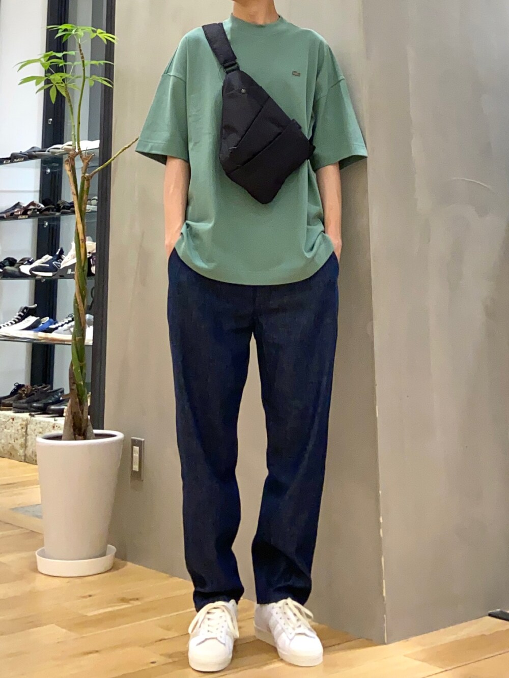 グリーン系のTシャツ/カットソー、ブラック系のショルダーバッグ、ブルー系のデニムパンツを着用したメンズの春コーディネートの3枚目の写真