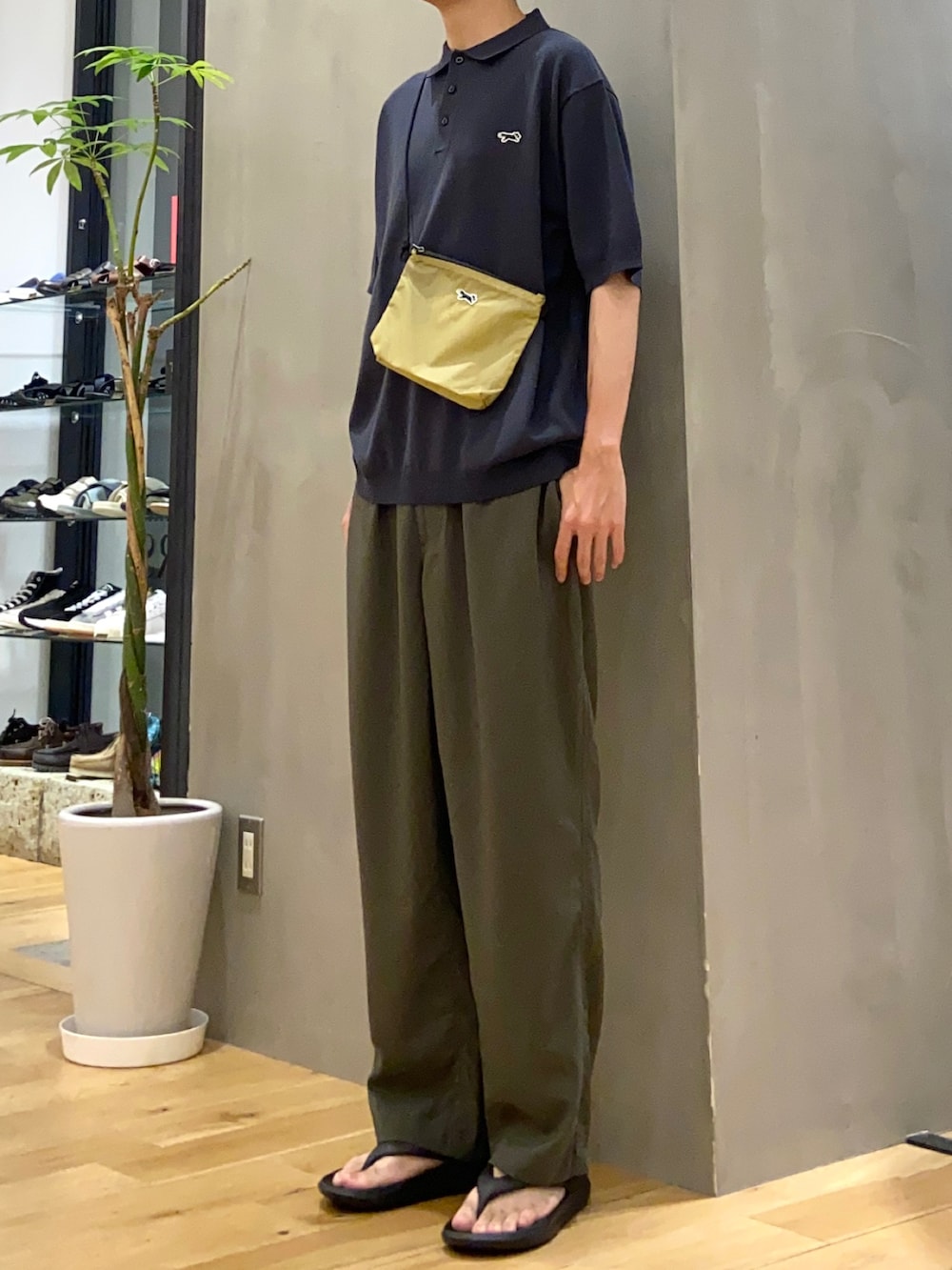 ブラック系のポロシャツ、ベージュ系のショルダーバッグ、グリーン系のその他パンツを着用したメンズの夏コーディネートの2枚目の写真