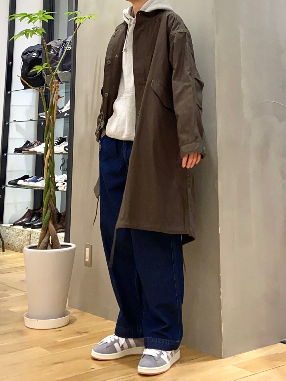 グレー系のパーカー、グリーン系のモッズコート、ブルー系のデニムパンツを着用したメンズの冬コーディネートの3枚目の写真