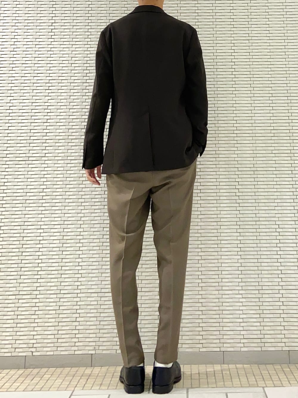 ブラウン系のスーツジャケット、ホワイト系のニット/セーター、ブラウン系のスーツパンツを着用したメンズの春コーディネートの3枚目の写真