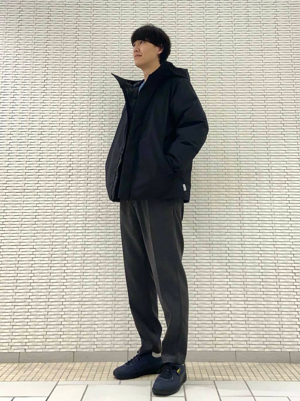 ブルー系のニット/セーター、ブラック系のダウンジャケット/コート、グレー系のその他パンツを着用したメンズの冬コーディネートの2枚目の写真
