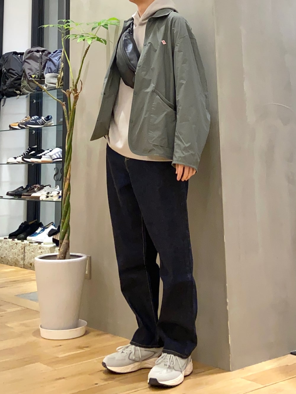 グリーン系のナイロンジャケット、ブラック系のボディバッグ/ウエストポーチ、ブルー系のデニムパンツを着用したメンズの冬コーディネートの3枚目の写真