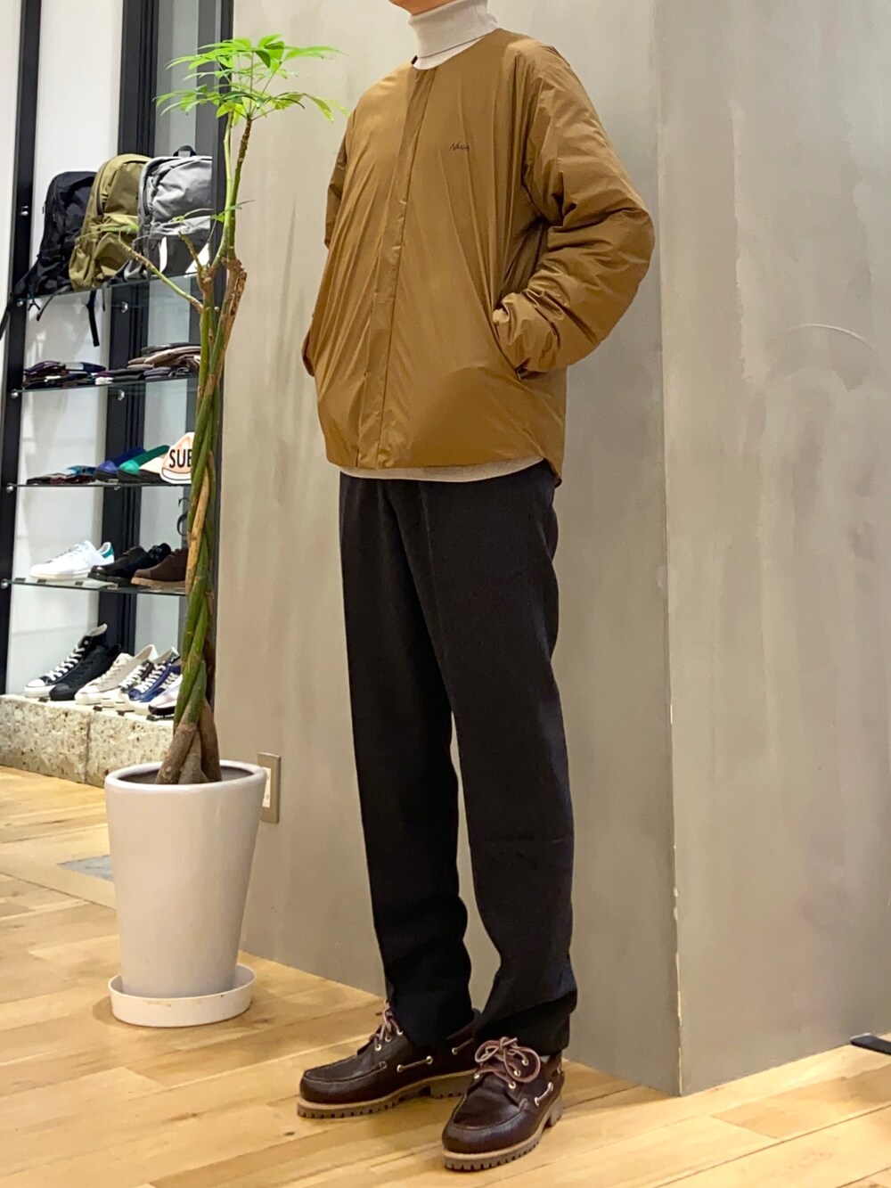 ベージュ系のダウンジャケット/コート、ベージュ系のニット/セーター、グレー系のその他パンツを着用したメンズの秋コーディネートの3枚目の写真