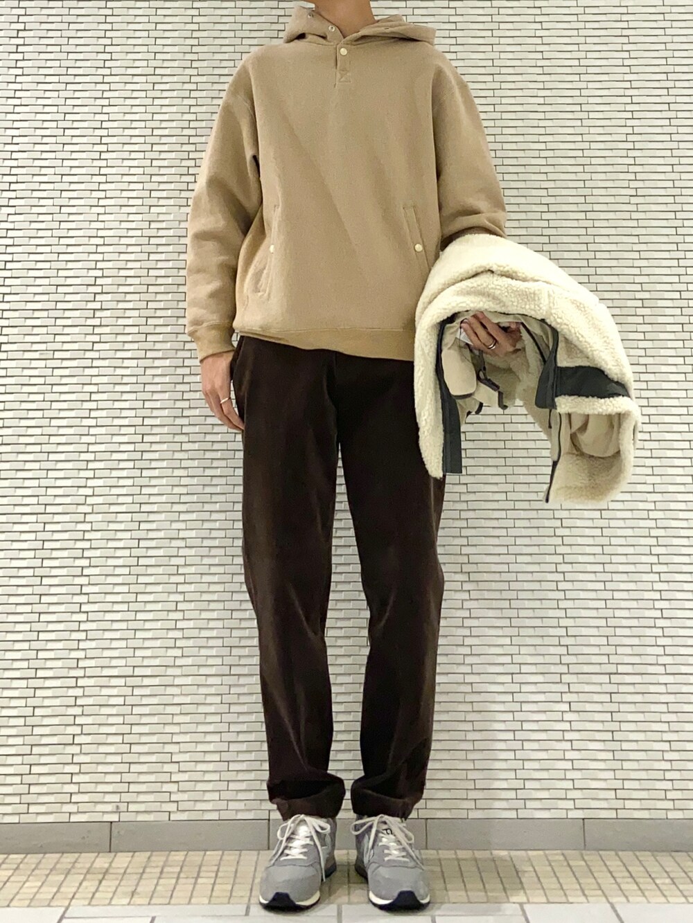 ホワイト系のブルゾン、ベージュ系のパーカー、ブラウン系のその他パンツを着用したメンズの冬コーディネートの2枚目の写真