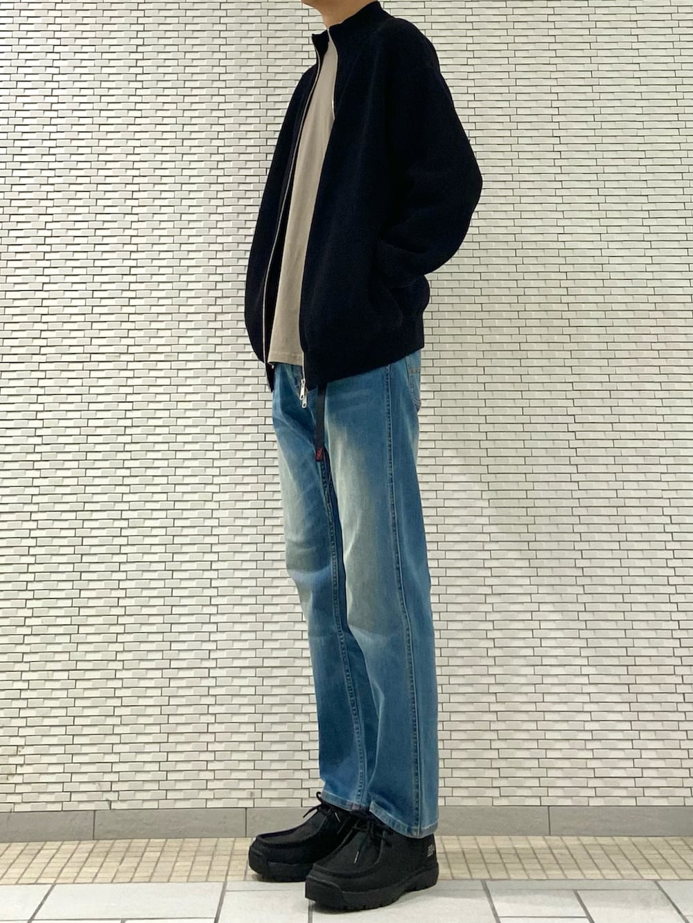 ブラック系のブルゾン、ブルー系のその他パンツ、ベージュ系のTシャツ/カットソーを着用したメンズの秋コーディネートの3枚目の写真