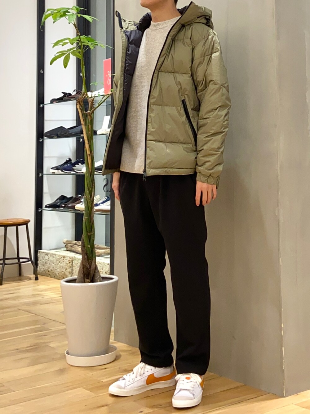 グリーン系のダウンジャケット/コート、ベージュ系のニット/セーター、オレンジ系のスニーカーを着用したメンズの冬コーディネートの2枚目の写真