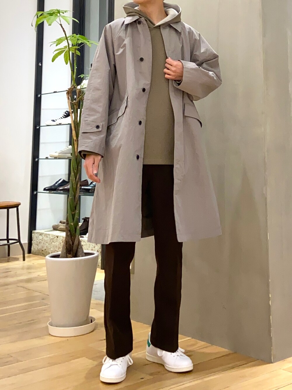 グレー系のステンカラーコート、グリーン系のパーカー、ブラウン系のその他パンツを着用したメンズの春コーディネートの4枚目の写真