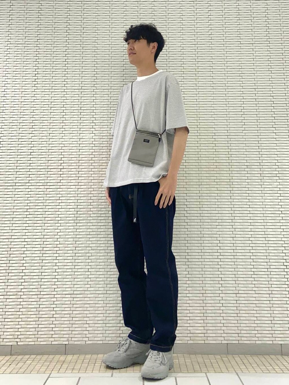 ホワイト系のTシャツ/カットソー、グレー系のスニーカー、ブルー系のデニムパンツを着用したメンズの夏コーディネートの2枚目の写真