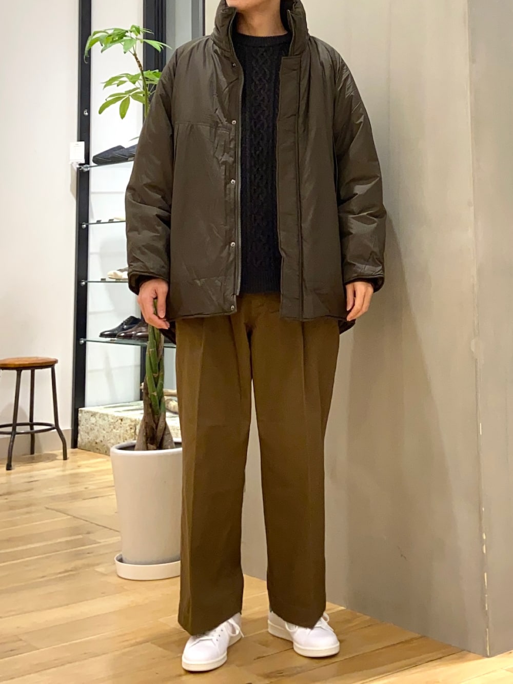 グリーン系のブルゾン、グレー系のニット/セーター、ホワイト系のスニーカーを着用したメンズの冬コーディネートの3枚目の写真
