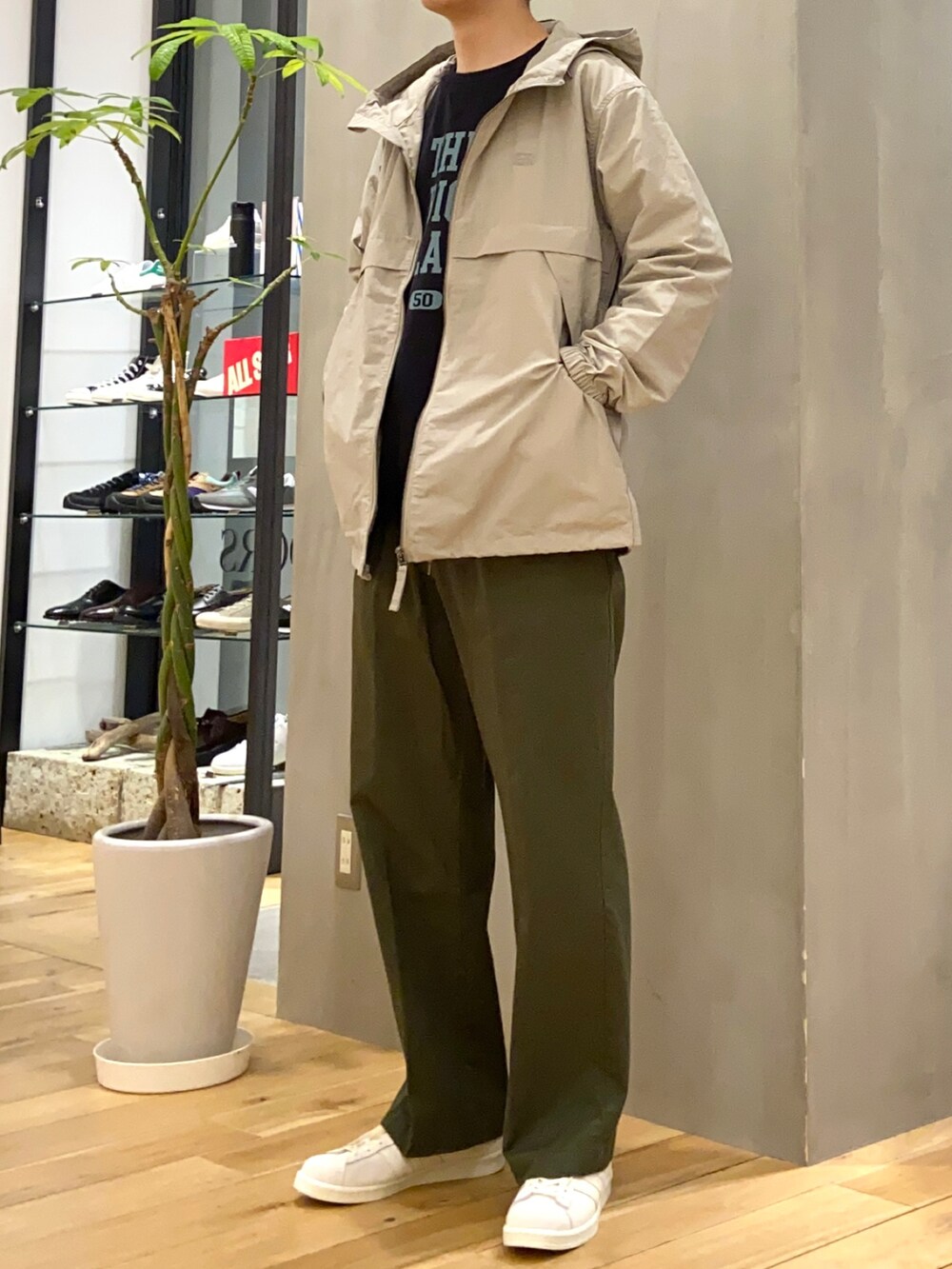 ベージュ系のマウンテンパーカー、ブラック系のスウェット、グリーン系のチノパンツを着用したメンズの春コーディネートの2枚目の写真