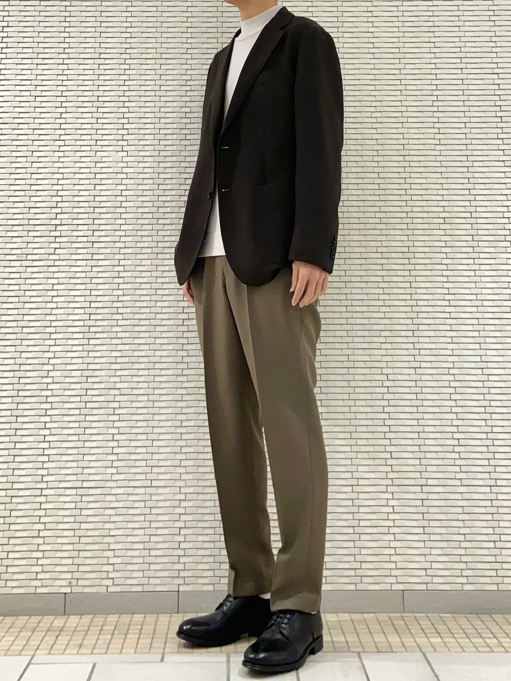 ブラウン系のスーツジャケット、ホワイト系のニット/セーター、ブラウン系のスーツパンツを着用したメンズの春コーディネートの2枚目の写真