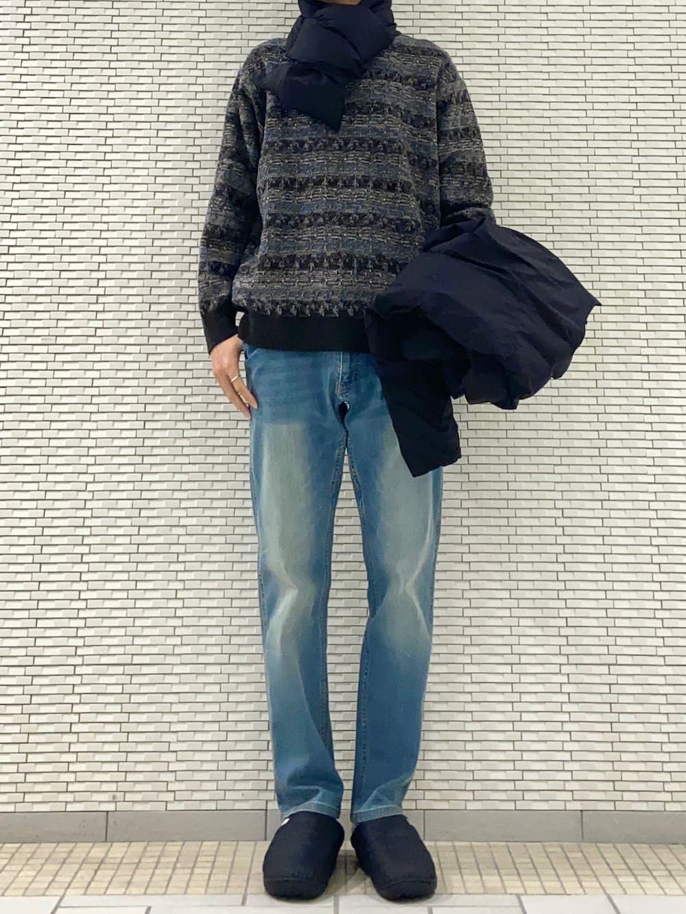 ブラック系のダウンジャケット/コート、グレー系のニット/セーター、ブルー系のその他パンツを着用したメンズの秋コーディネートの2枚目の写真