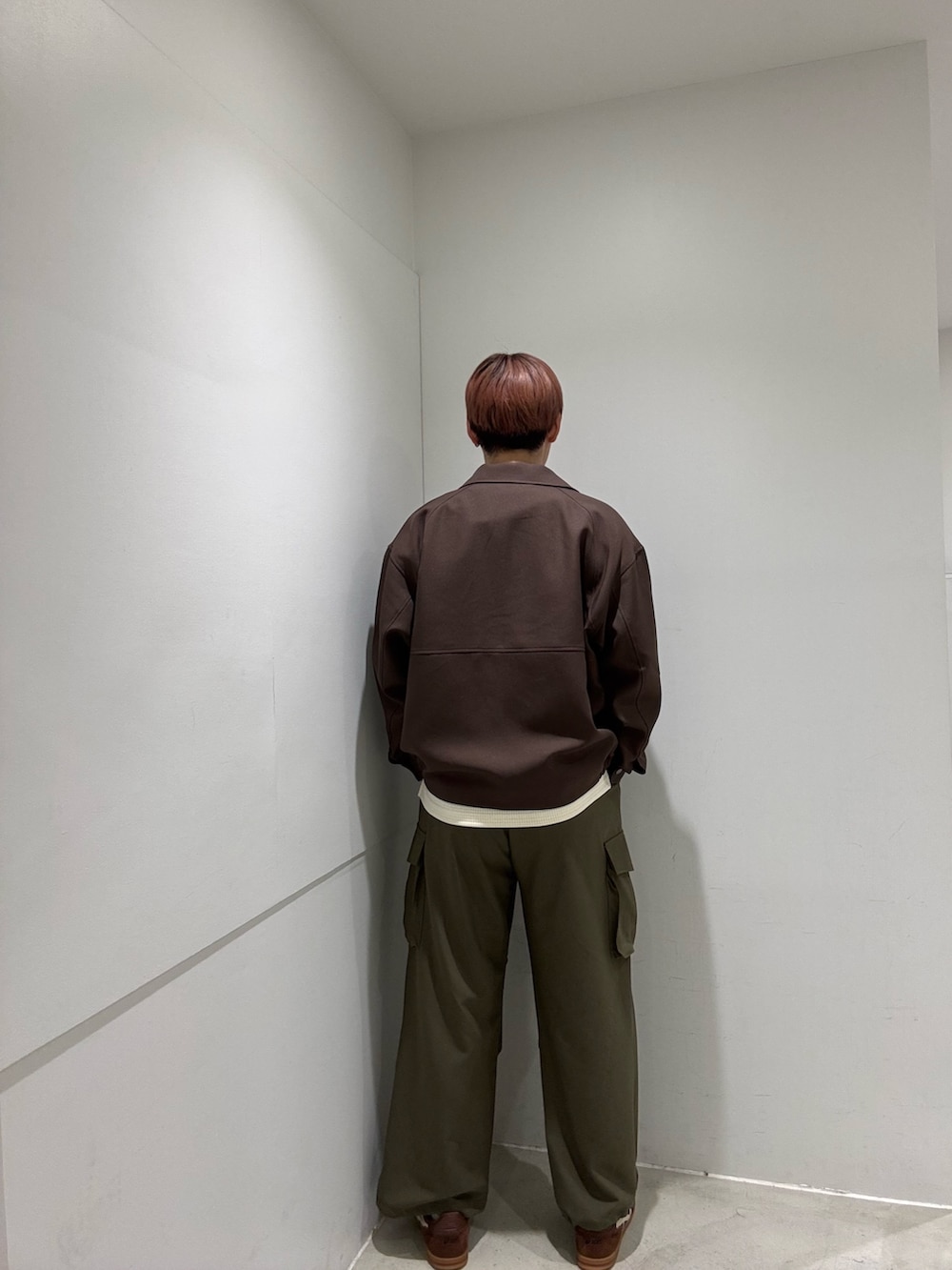 ホワイト系のTシャツ/カットソー、ブラウン系のブルゾン、グリーン系のカーゴパンツを着用したメンズの冬コーディネートの3枚目の写真