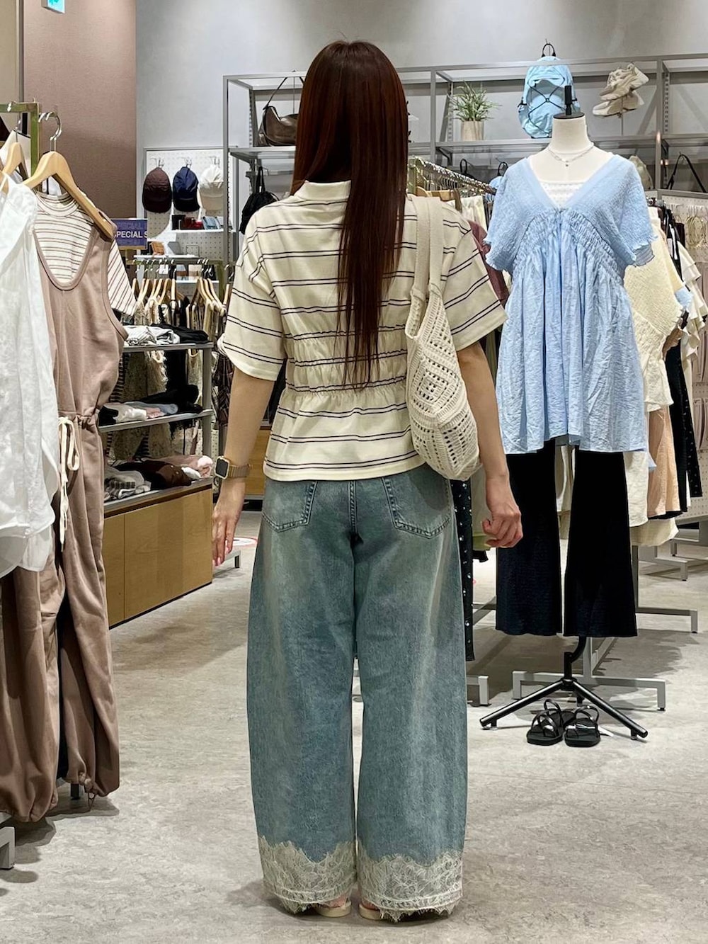 ブルー系のデニムパンツ、ホワイト系のサンダル、ホワイト系のトートバッグを着用したレディースの夏コーディネートの4枚目の写真