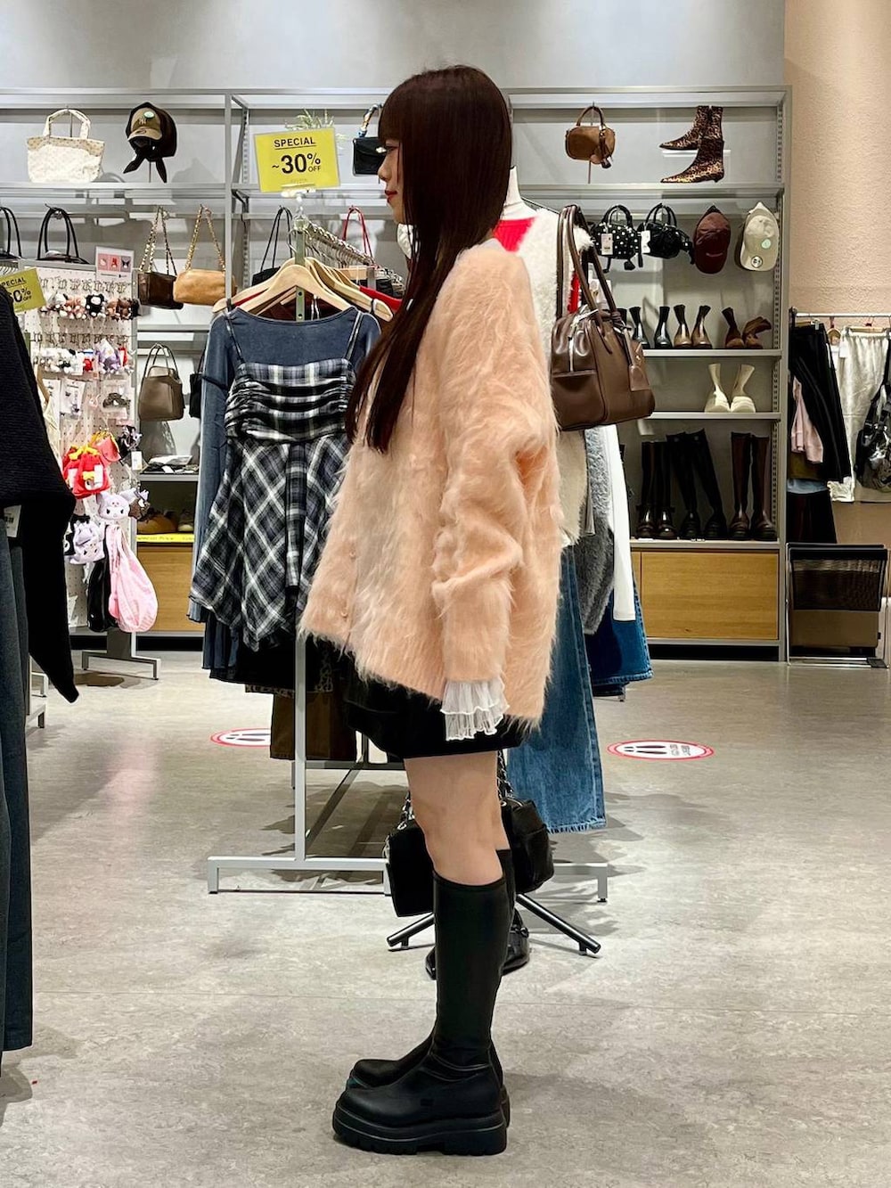 ブラック系のスカート、ホワイト系のTシャツ/カットソー、ブラック系のブーツを着用したレディースの秋コーディネートの3枚目の写真