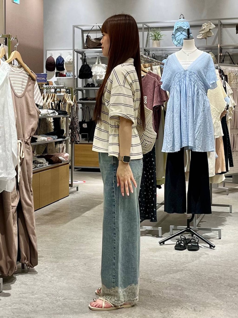 ブルー系のデニムパンツ、ホワイト系のサンダル、ホワイト系のトートバッグを着用したレディースの夏コーディネートの3枚目の写真