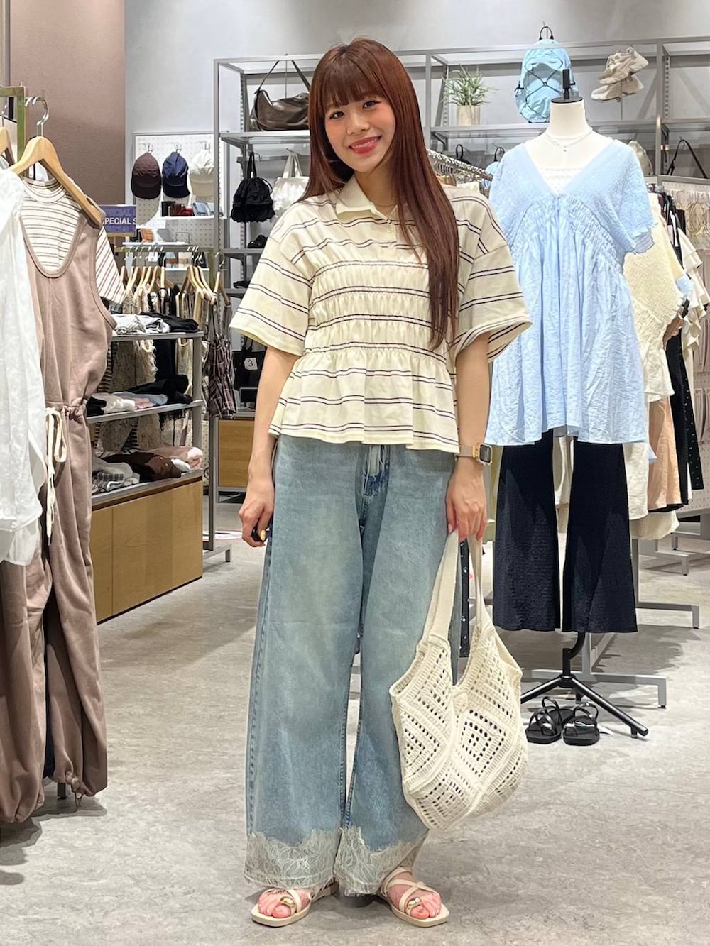 ブルー系のデニムパンツ、ホワイト系のサンダル、ホワイト系のトートバッグを着用したレディースの夏コーディネートの2枚目の写真