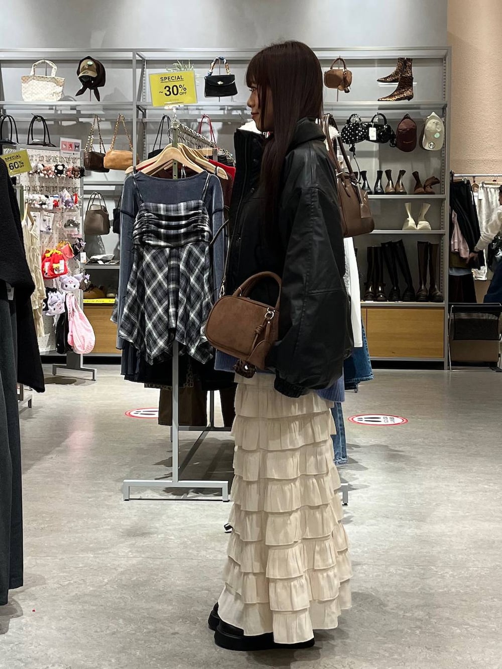 ホワイト系のスカート、ブラック系のサンダル、ブラック系のブルゾンを着用したレディースの秋コーディネートの3枚目の写真