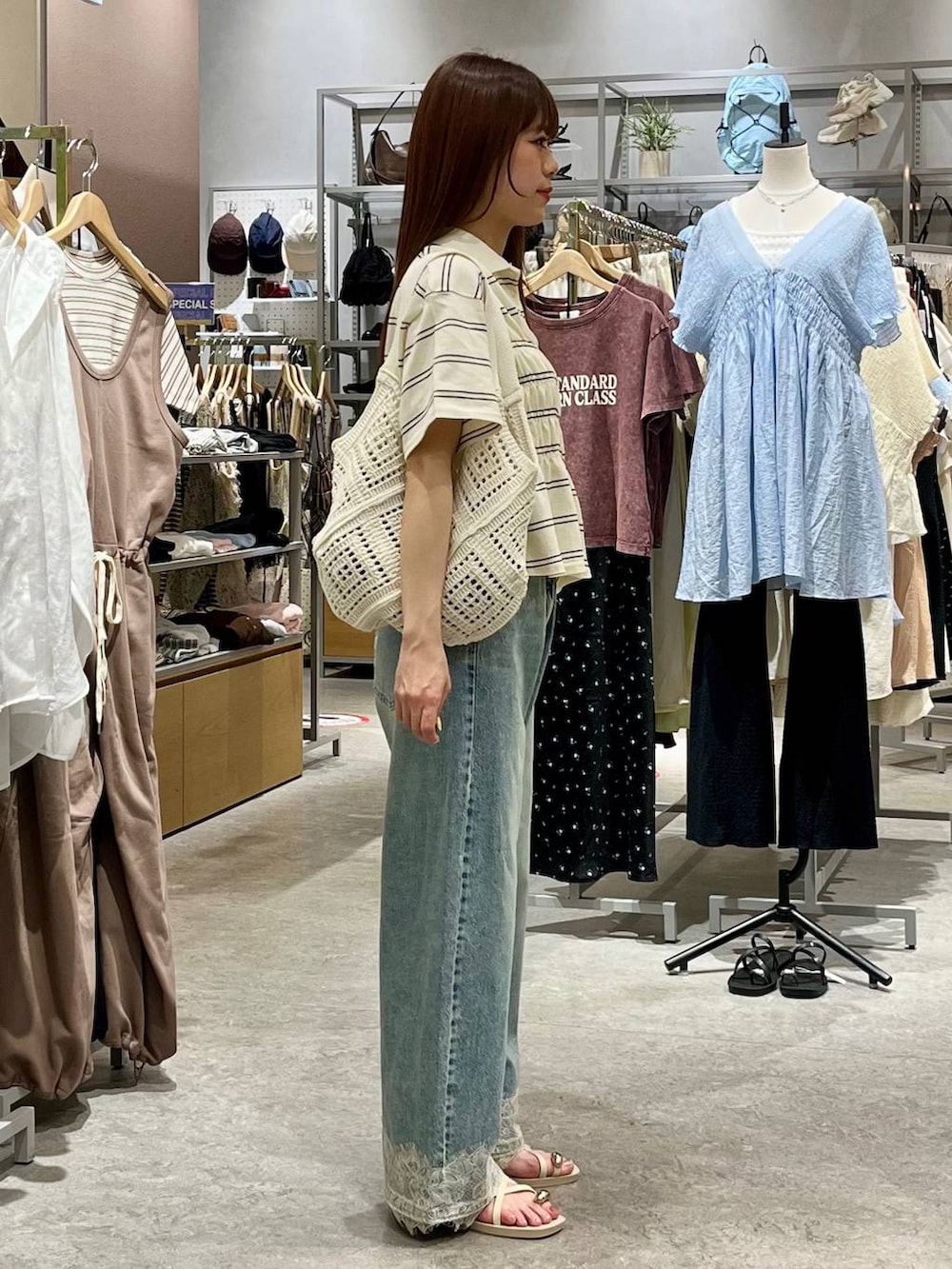 ブルー系のデニムパンツ、ホワイト系のサンダル、ホワイト系のトートバッグを着用したレディースの夏コーディネートの5枚目の写真