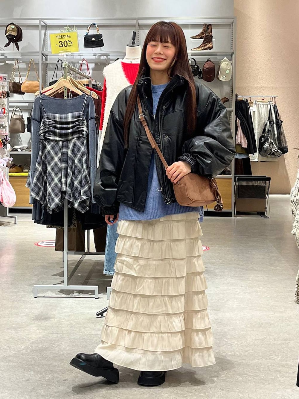 ホワイト系のスカート、ブラック系のサンダル、ブラック系のブルゾンを着用したレディースの秋コーディネートの2枚目の写真