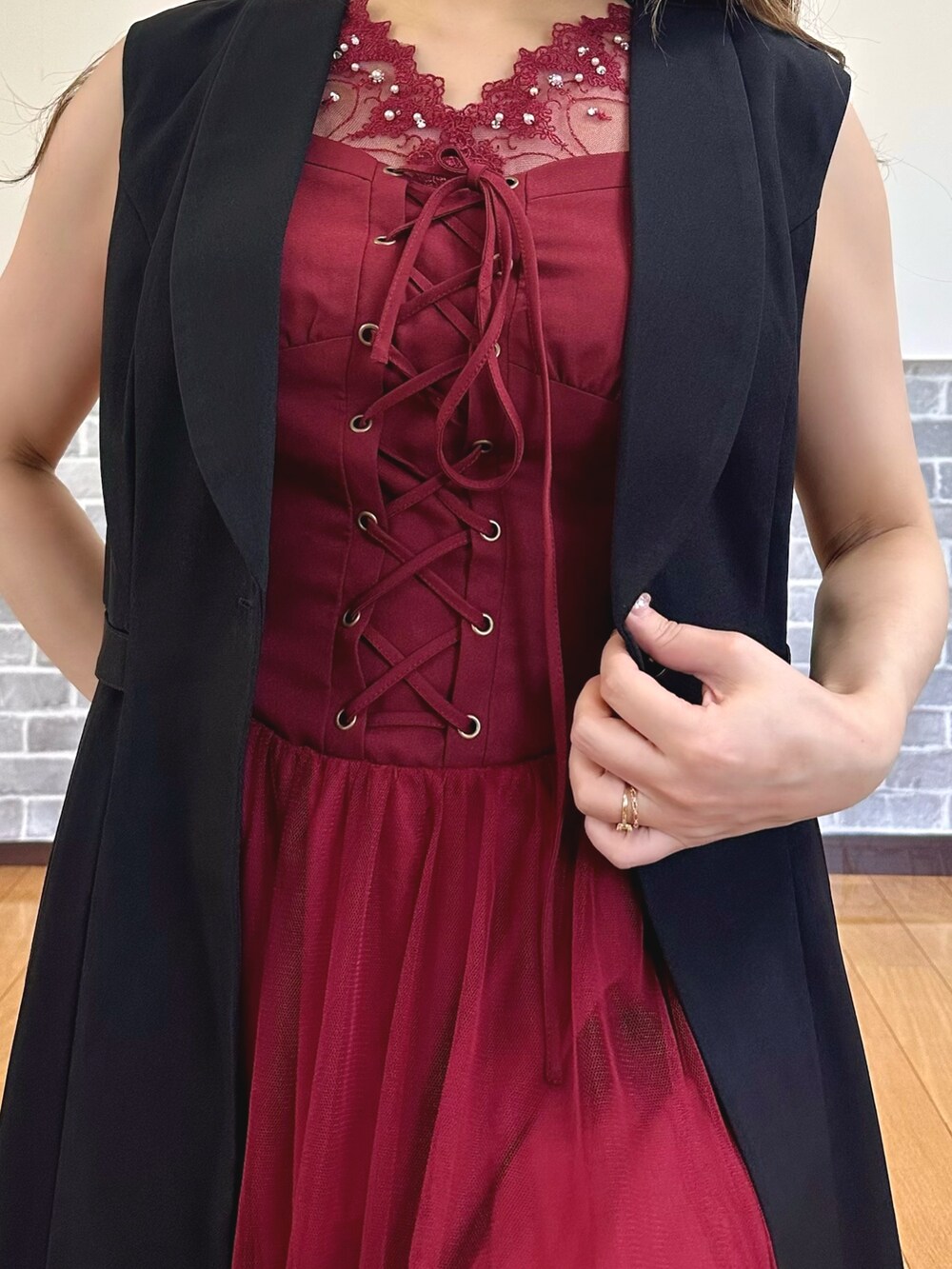 レッド系のタンクトップ、レッド系のジャンパースカート、ブラック系のベストを着用したレディースの夏コーディネートの6枚目の写真