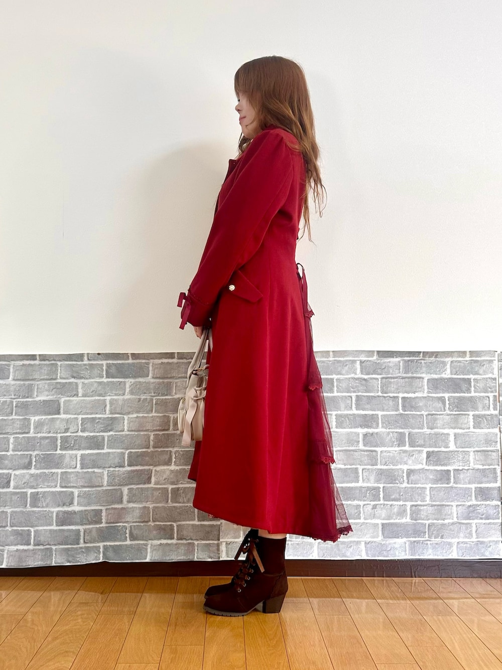 レッド系のダッフルコート、ホワイト系のTシャツ/カットソー、ホワイト系のニット/セーターを着用したレディースの冬コーディネートの3枚目の写真