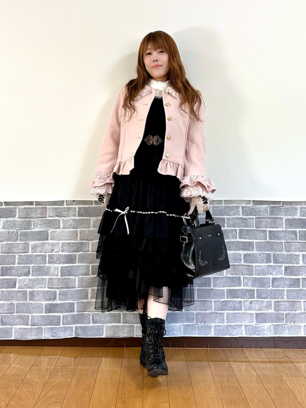 ピンク系のピーコート、ブラック系のスカート、ブラック系のボストンバッグを着用したレディースの秋コーディネートの2枚目の写真