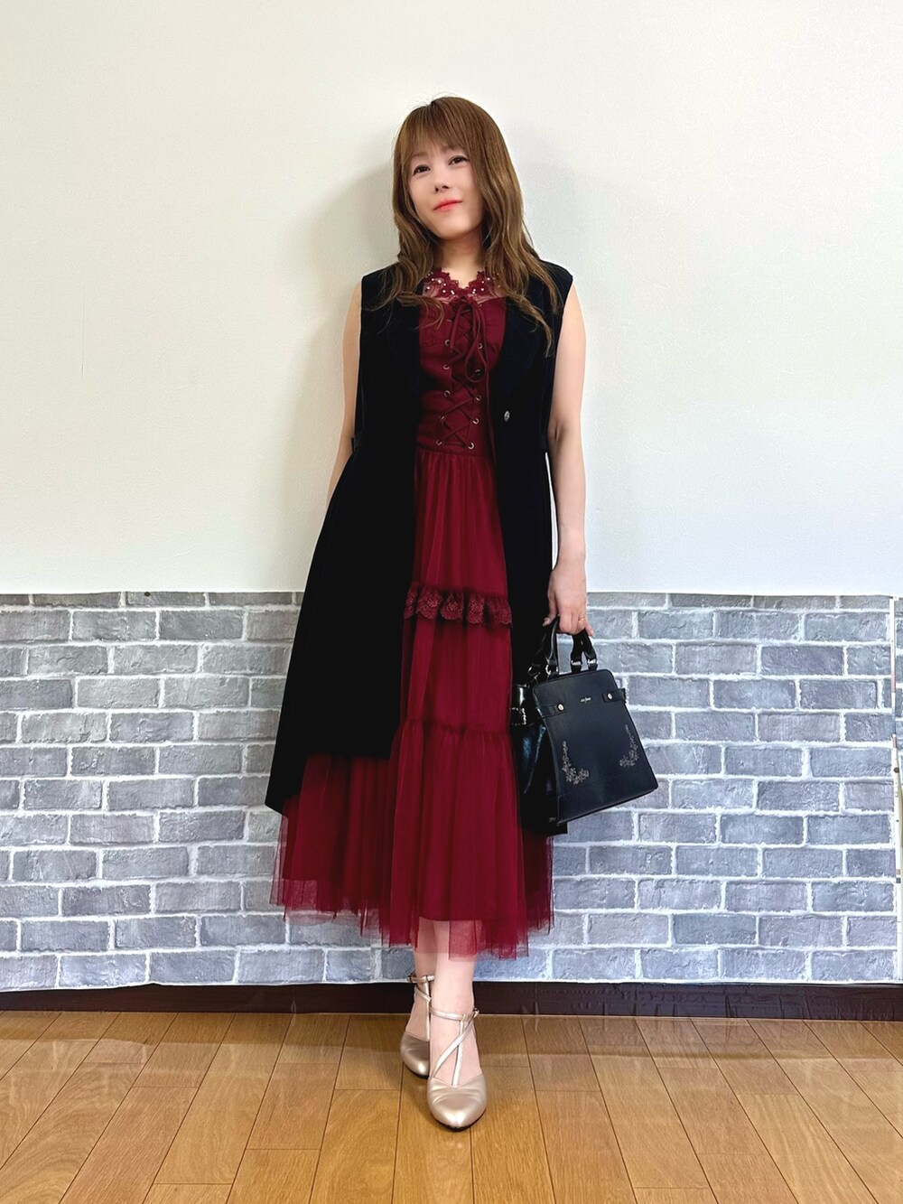 レッド系のタンクトップ、レッド系のジャンパースカート、ブラック系のベストを着用したレディースの夏コーディネートの2枚目の写真