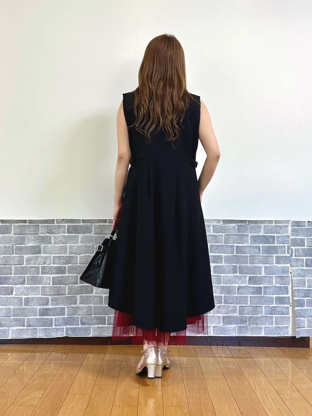 レッド系のタンクトップ、レッド系のジャンパースカート、ブラック系のベストを着用したレディースの夏コーディネートの4枚目の写真