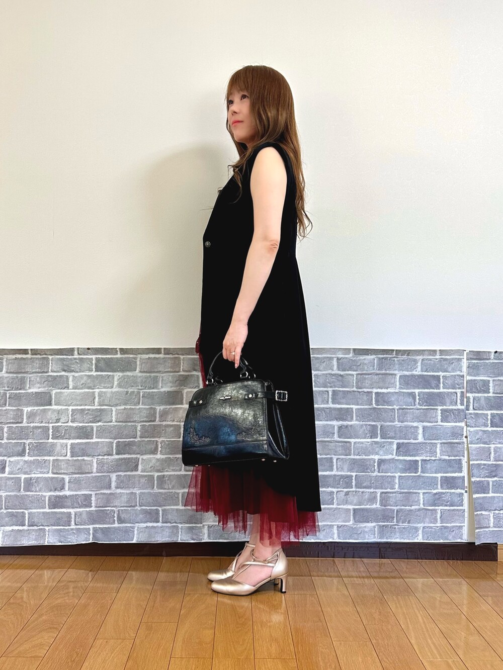 レッド系のタンクトップ、レッド系のジャンパースカート、ブラック系のベストを着用したレディースの夏コーディネートの3枚目の写真