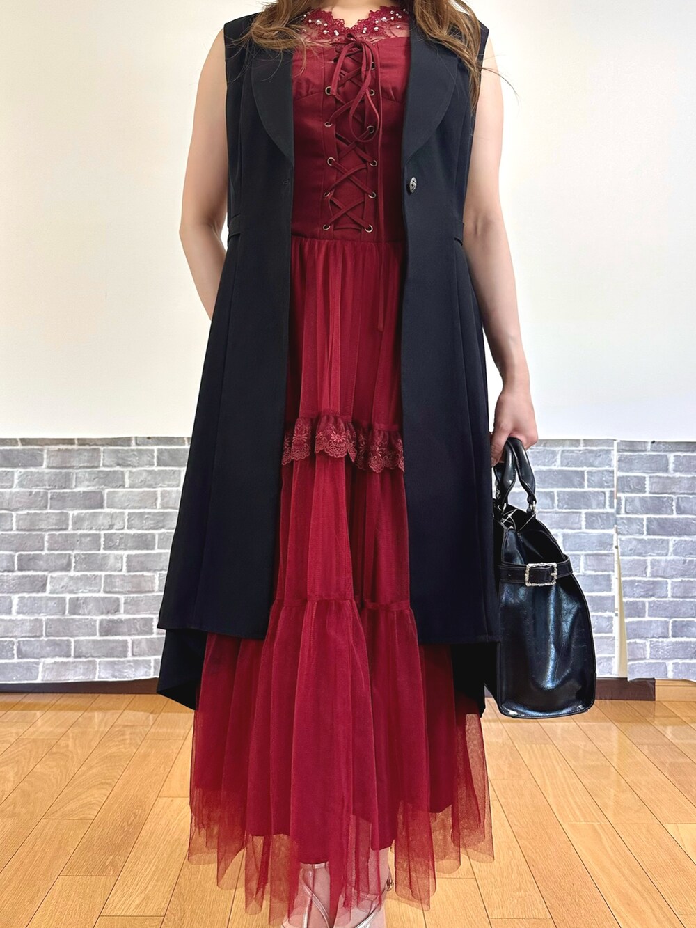 レッド系のタンクトップ、レッド系のジャンパースカート、ブラック系のベストを着用したレディースの夏コーディネートの5枚目の写真