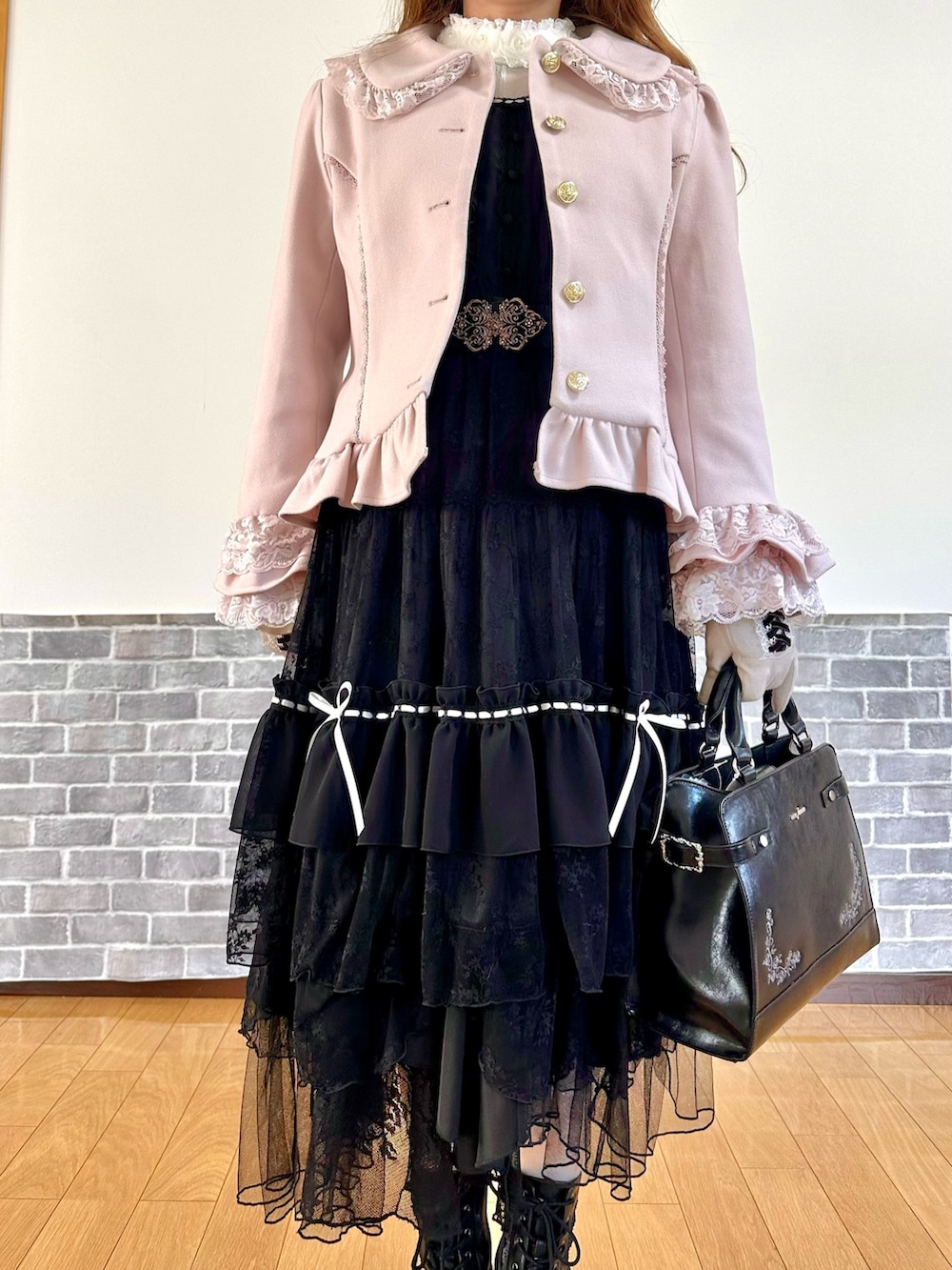 ピンク系のピーコート、ブラック系のスカート、ブラック系のボストンバッグを着用したレディースの秋コーディネートの6枚目の写真