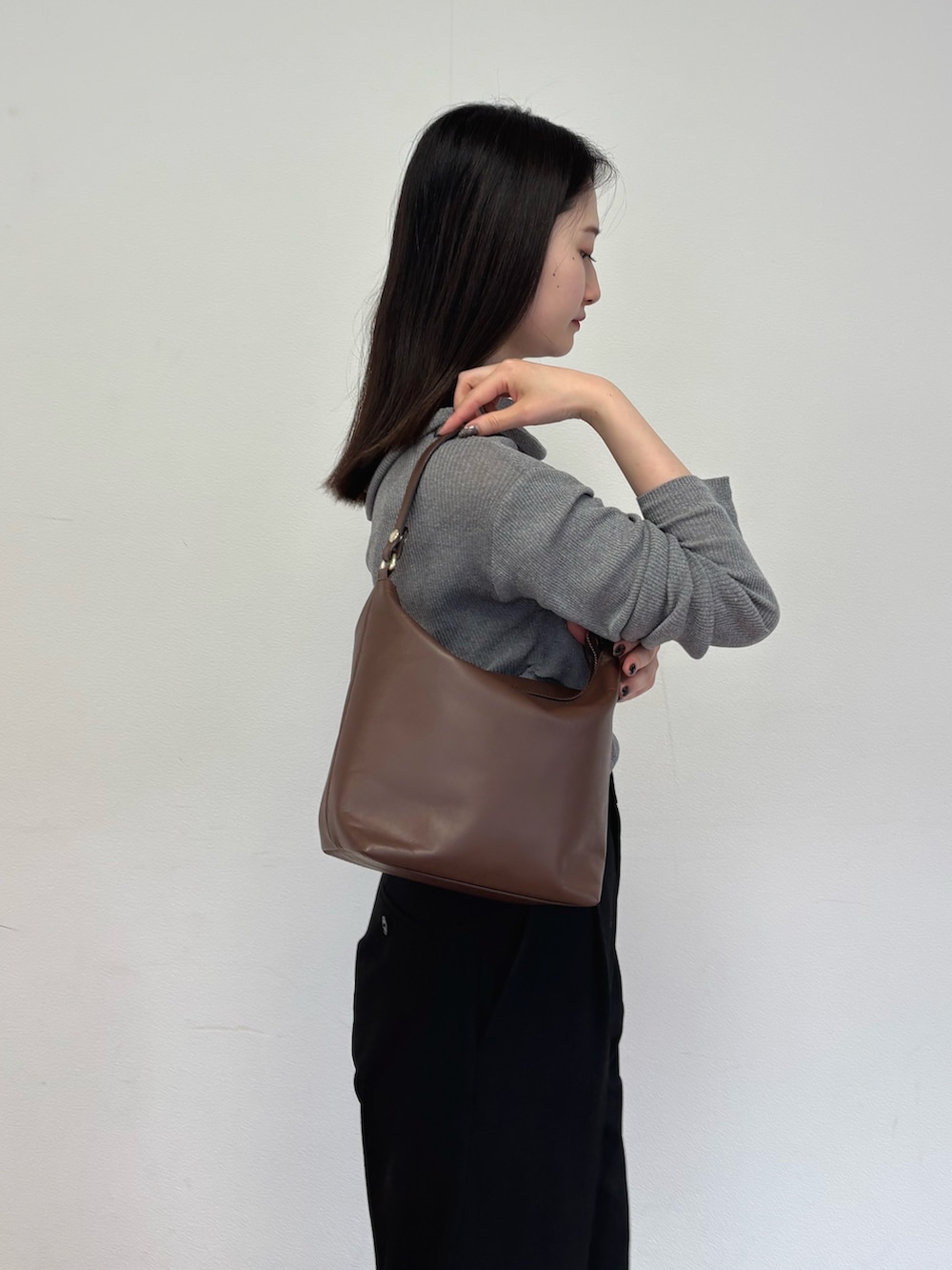 ブラウン系のショルダーバッグ、グレー系のニット/セーターを着用したレディースの春コーディネートの2枚目の写真