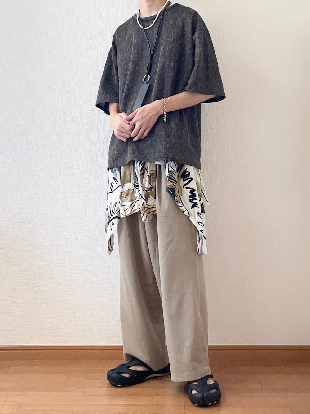 ブラウン系のTシャツ/カットソー、ベージュ系のスラックス、ブラック系のサンダルを着用したメンズの夏コーディネートの2枚目の写真