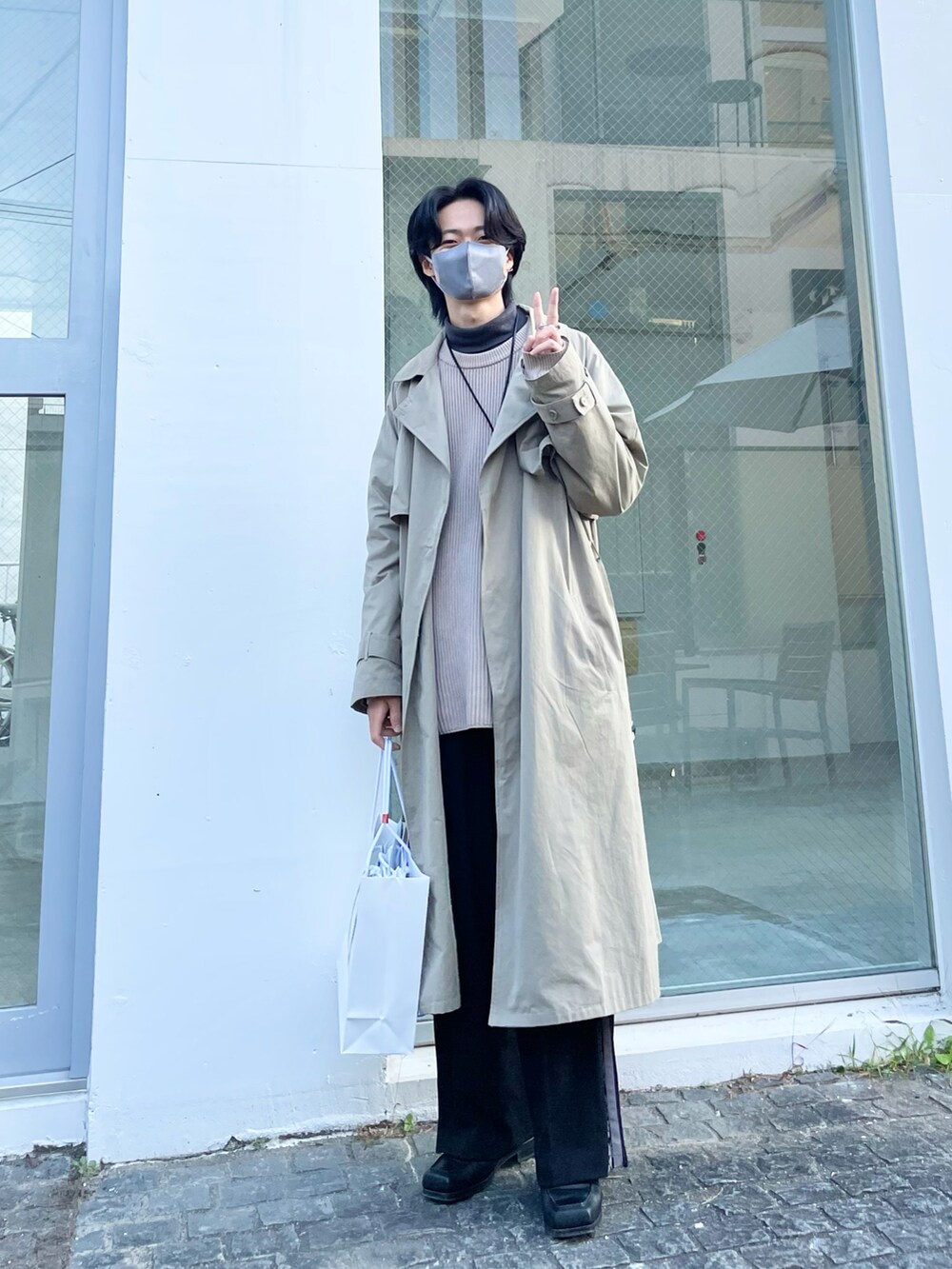 グリーン系のトレンチコート、ベージュ系のニット/セーター、グレー系のTシャツ/カットソーを着用したメンズの春コーディネートの3枚目の写真