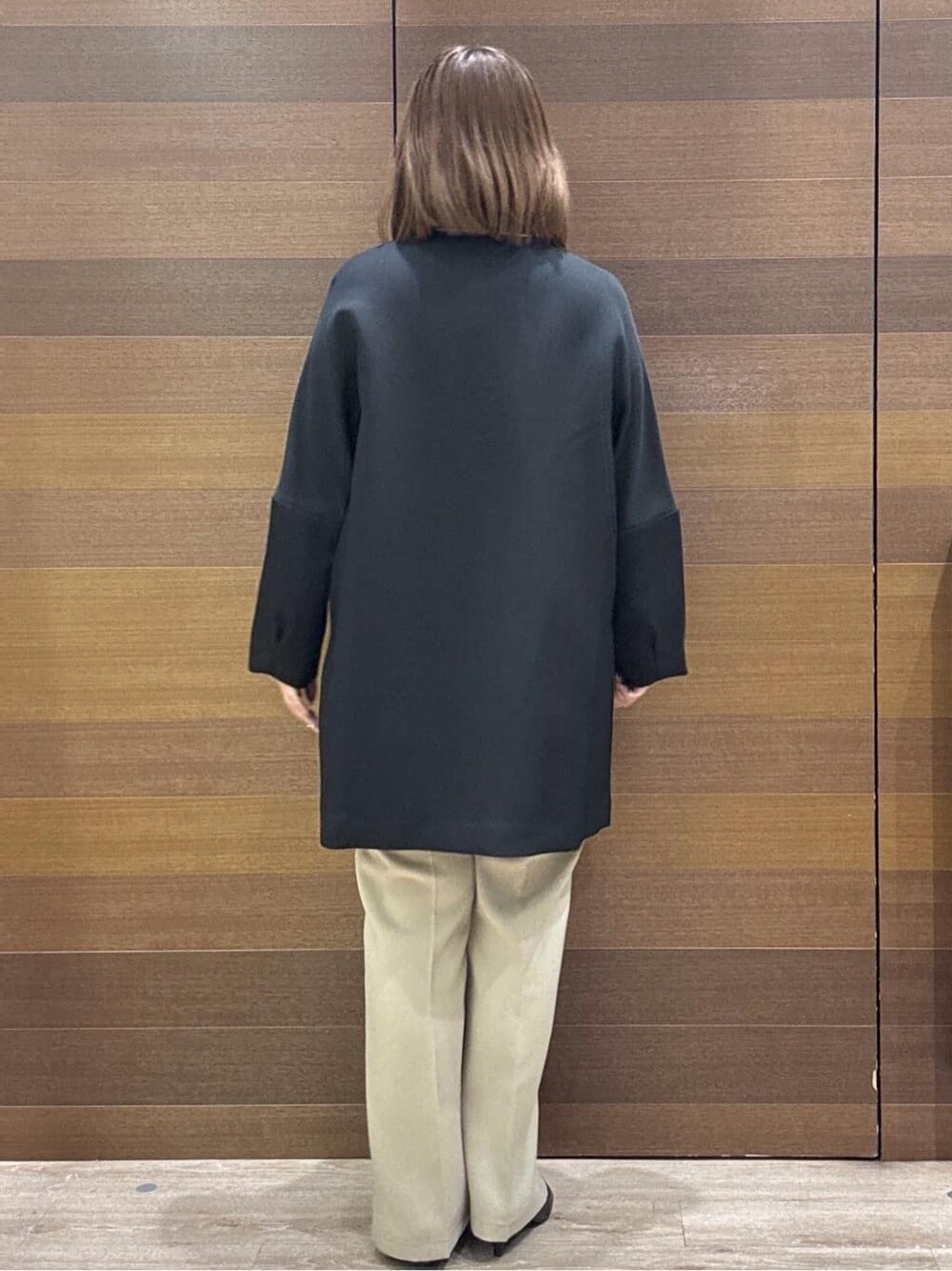 ブラック系のノーカラーコート、ベージュ系のその他パンツ、ホワイト系のハンドバッグを着用したレディースの冬コーディネートの9枚目の写真