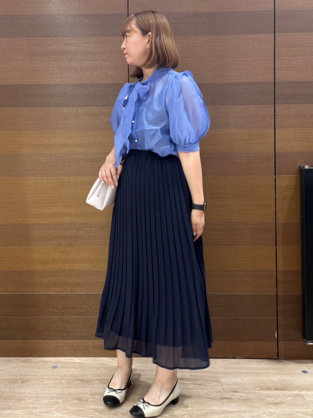 ブルー系のスカート、グレー系のショルダーバッグ、ベージュ系のパンプスを着用したレディースの夏コーディネートの4枚目の写真