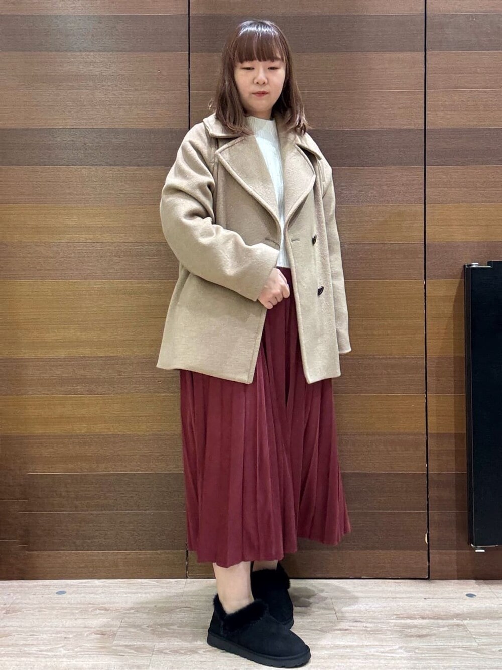 ベージュ系のピーコート、ホワイト系のニット/セーター、レッド系のスカートを着用したレディースの冬コーディネートの4枚目の写真