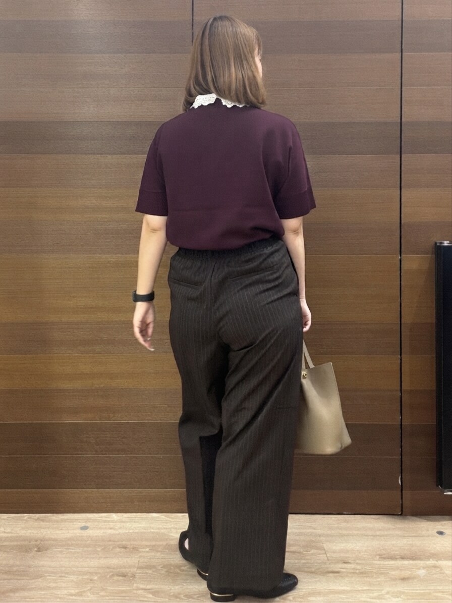 レッド系のニット/セーター、ブラウン系のその他パンツ、ベージュ系のショルダーバッグを着用したレディースの秋コーディネートの5枚目の写真