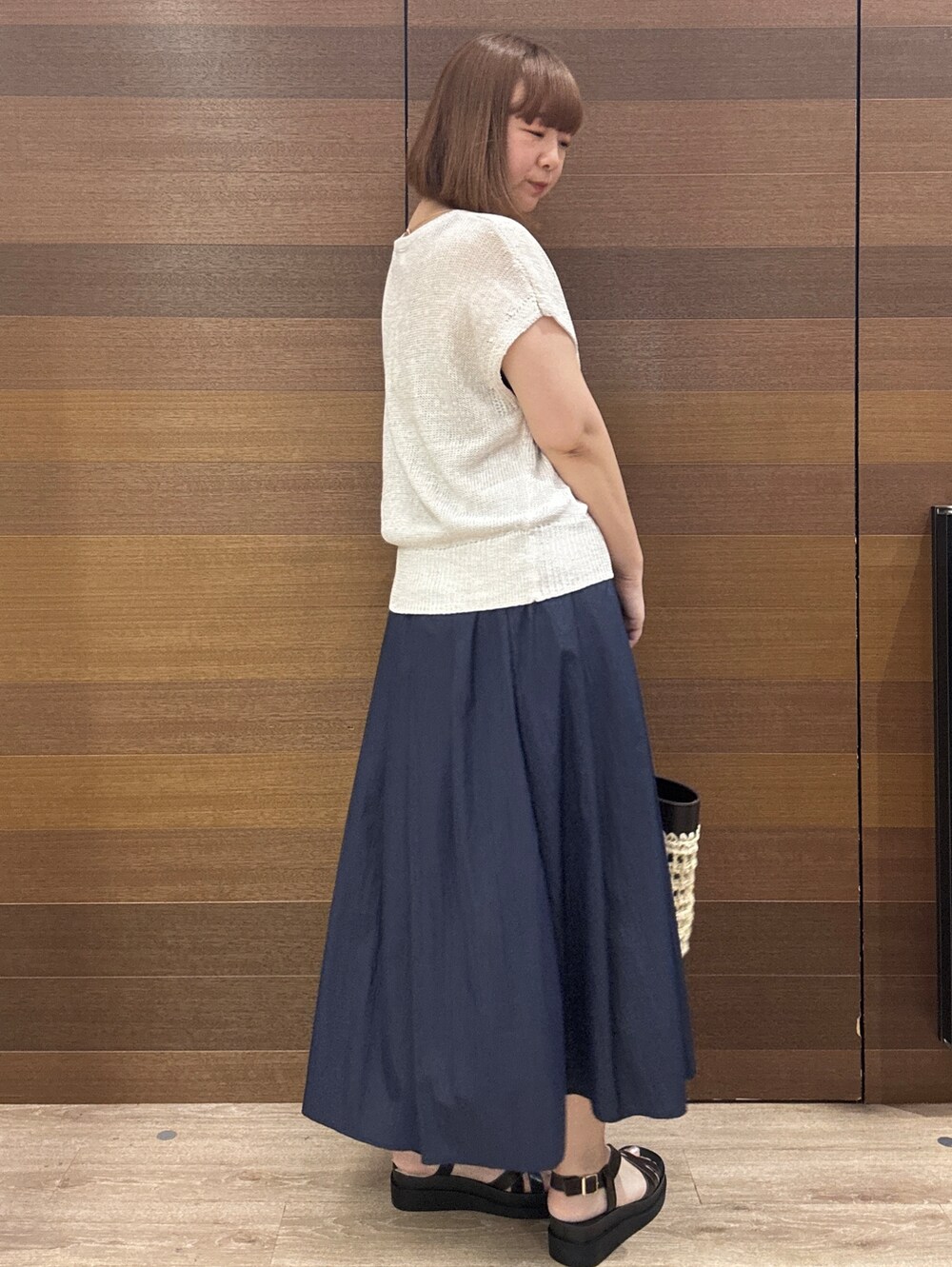 ホワイト系のニット/セーター、ブルー系のスカート、ブラック系のトートバッグを着用したレディースの夏コーディネートの5枚目の写真