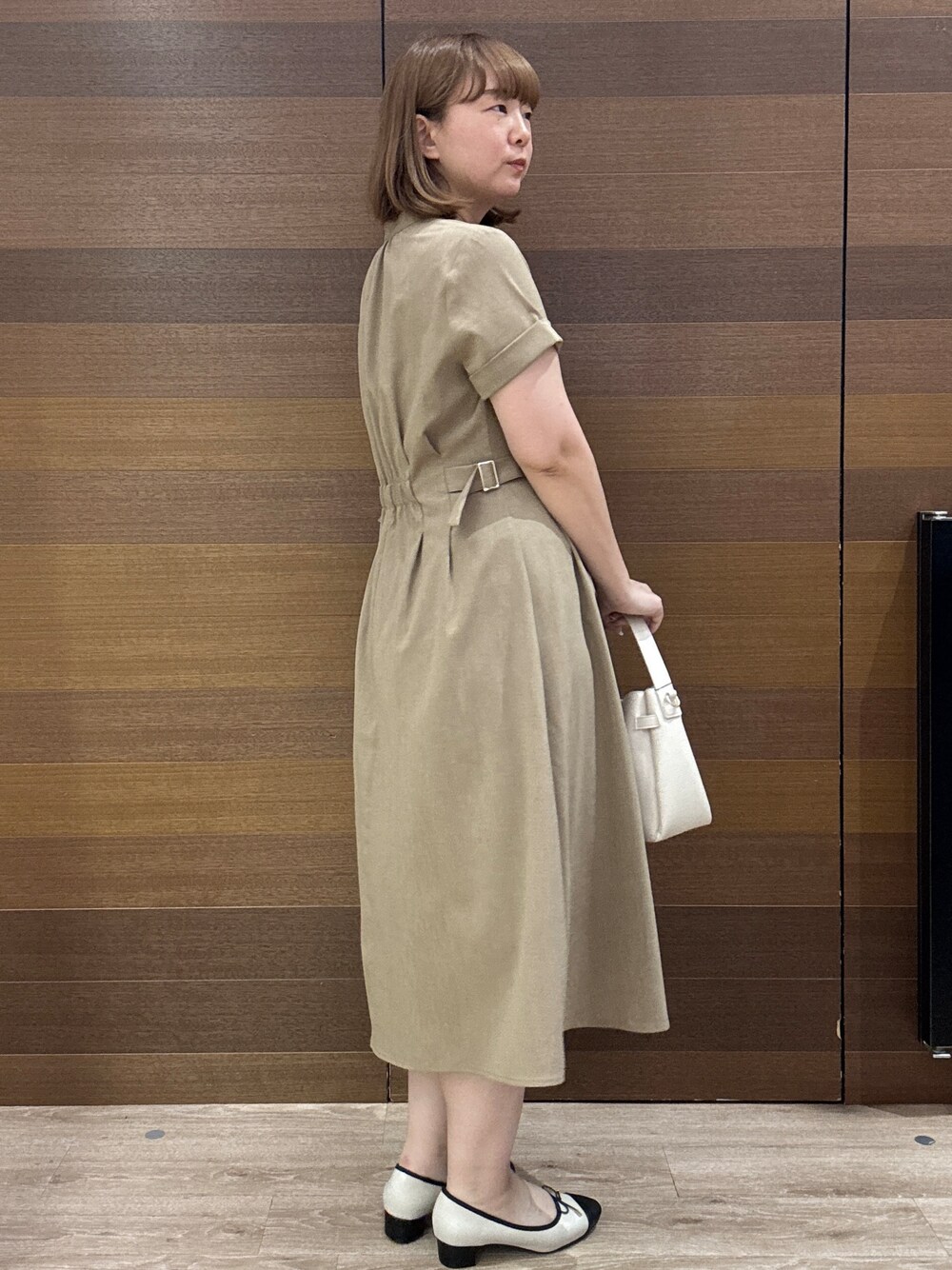イエロー系のワンピース、ホワイト系のトートバッグ、ベージュ系のパンプスを着用したレディースの夏コーディネートの5枚目の写真
