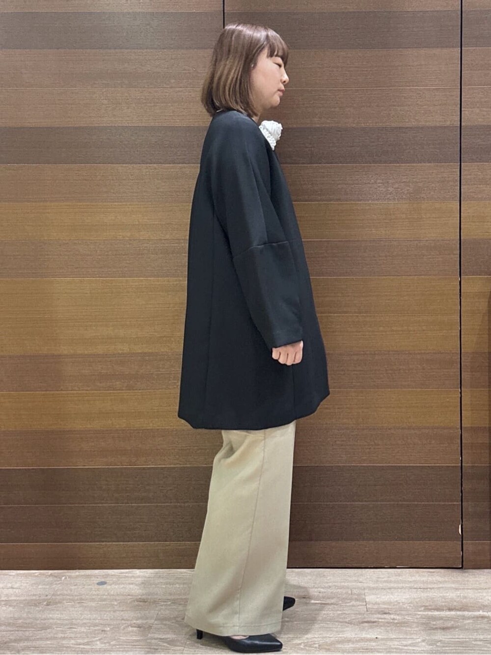 ブラック系のノーカラーコート、ベージュ系のその他パンツ、ホワイト系のハンドバッグを着用したレディースの冬コーディネートの8枚目の写真
