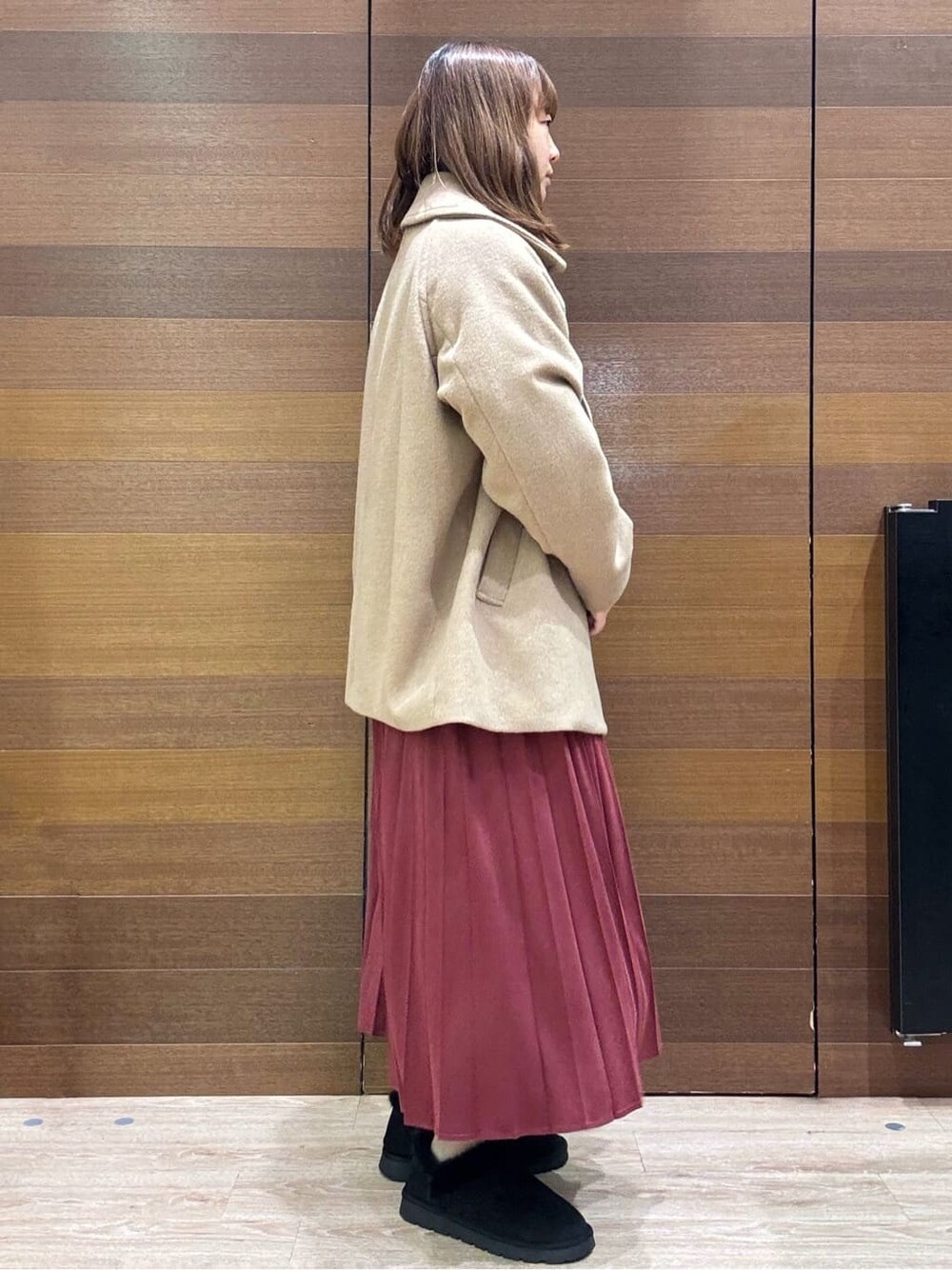 ベージュ系のピーコート、ホワイト系のニット/セーター、レッド系のスカートを着用したレディースの冬コーディネートの5枚目の写真